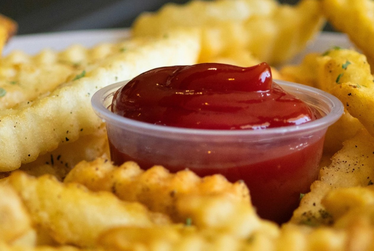 Crinkle-cut fries around a cup of ketchup